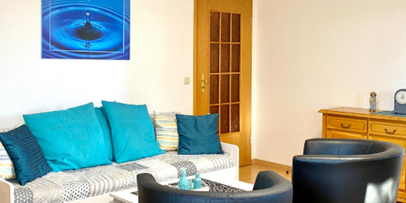 Wohnzimmer der Wohnung 7. Schlafcouch zwei sessel, blaues Bild an der Wand