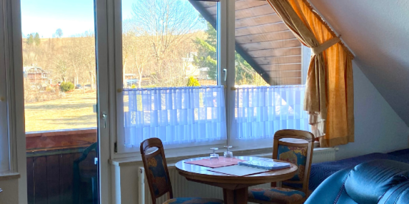 Wohnzimmer Wohnung Klatschmohn mit Balkon und schwarter Ledercouch und Esstisch